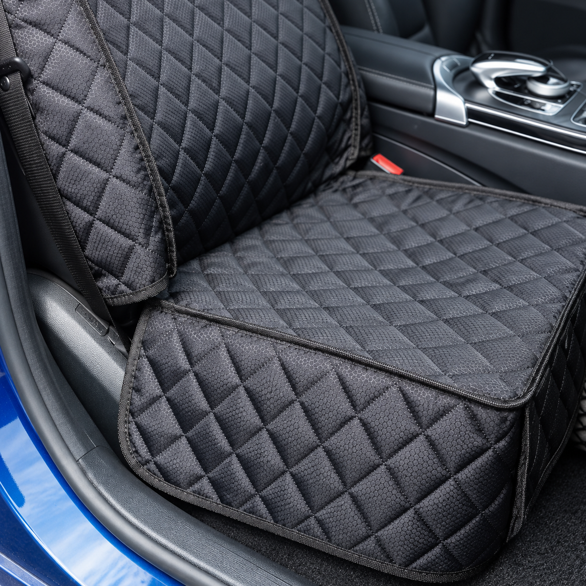 Detail view of Black quilted pet seat cover fabric, stitched edging, and straps in a car - Ravzelo